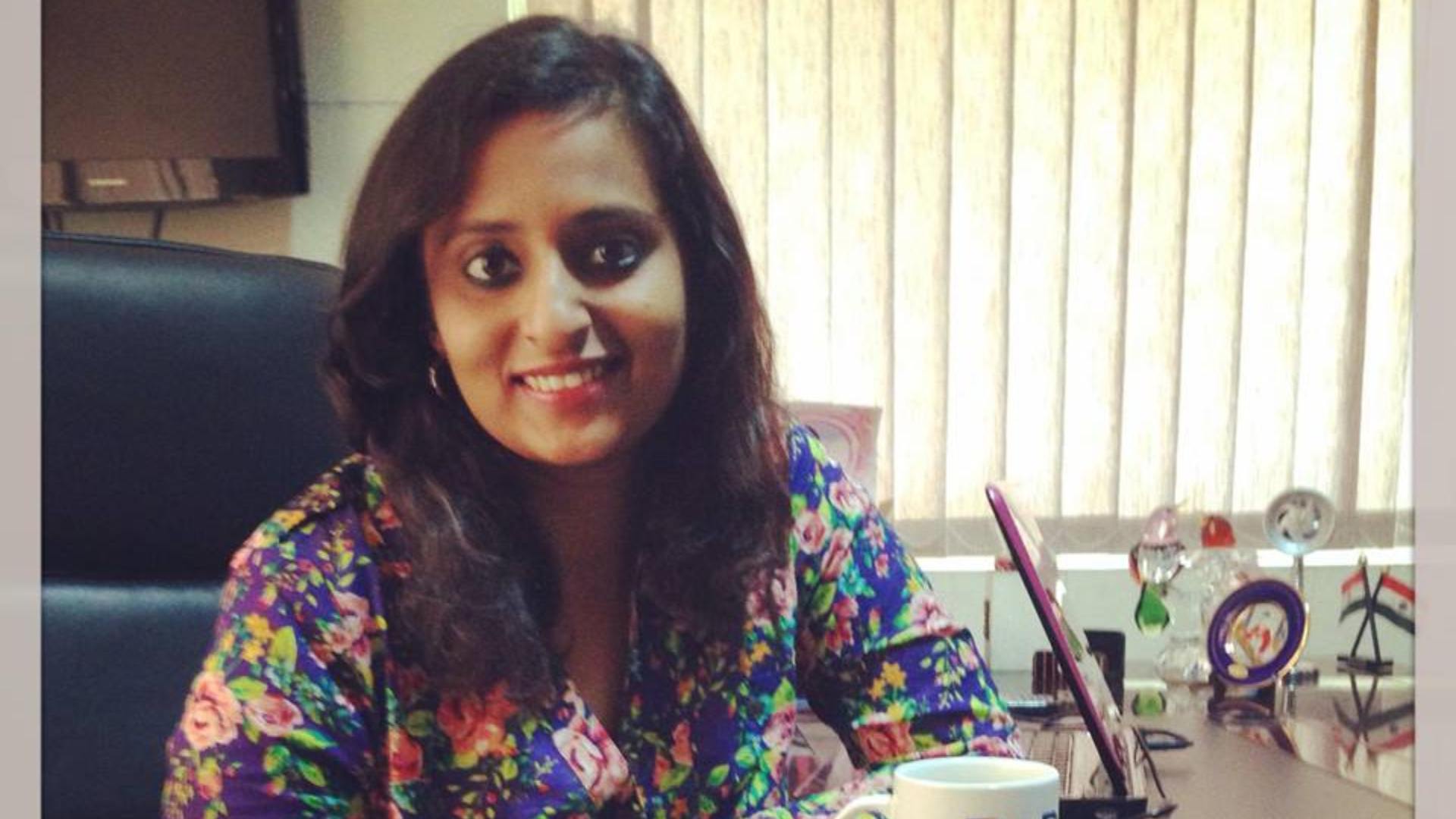 A woman smiling confidently while seated at her desk, surrounded by awards and national flags, representing determination and readiness to shape her future.